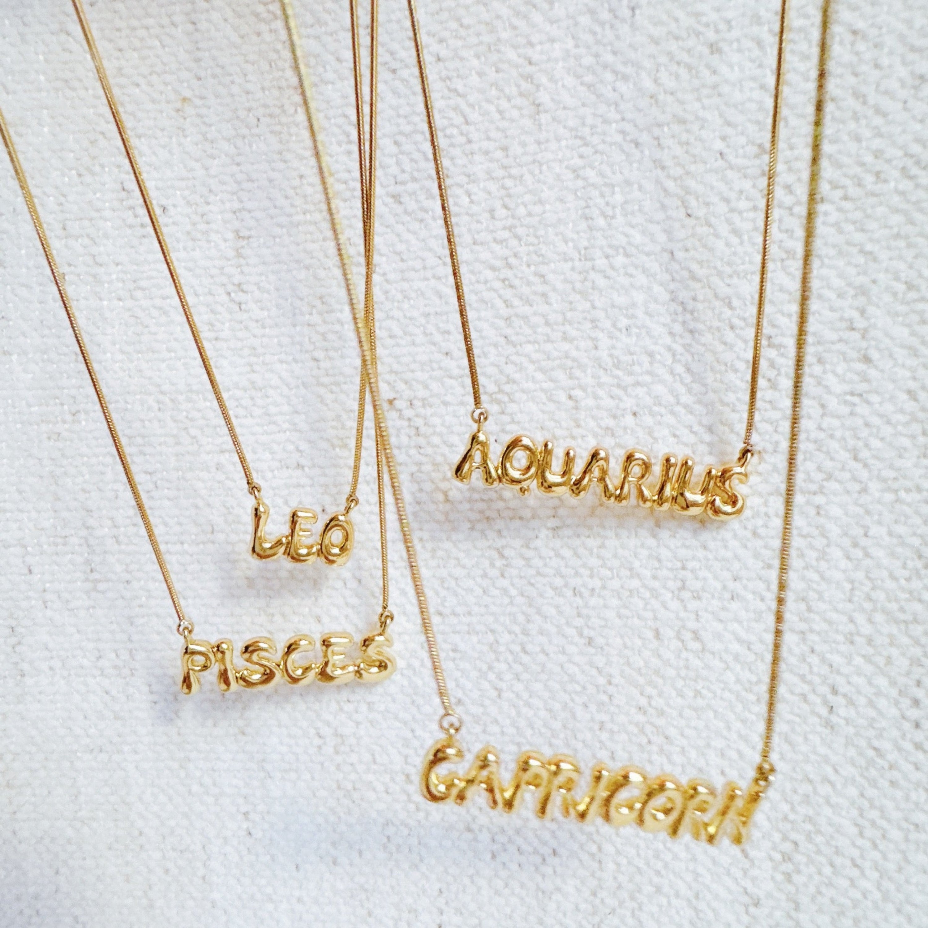 Balloon Letter Zodiac Necklace - multiple zodiac signs flat lay