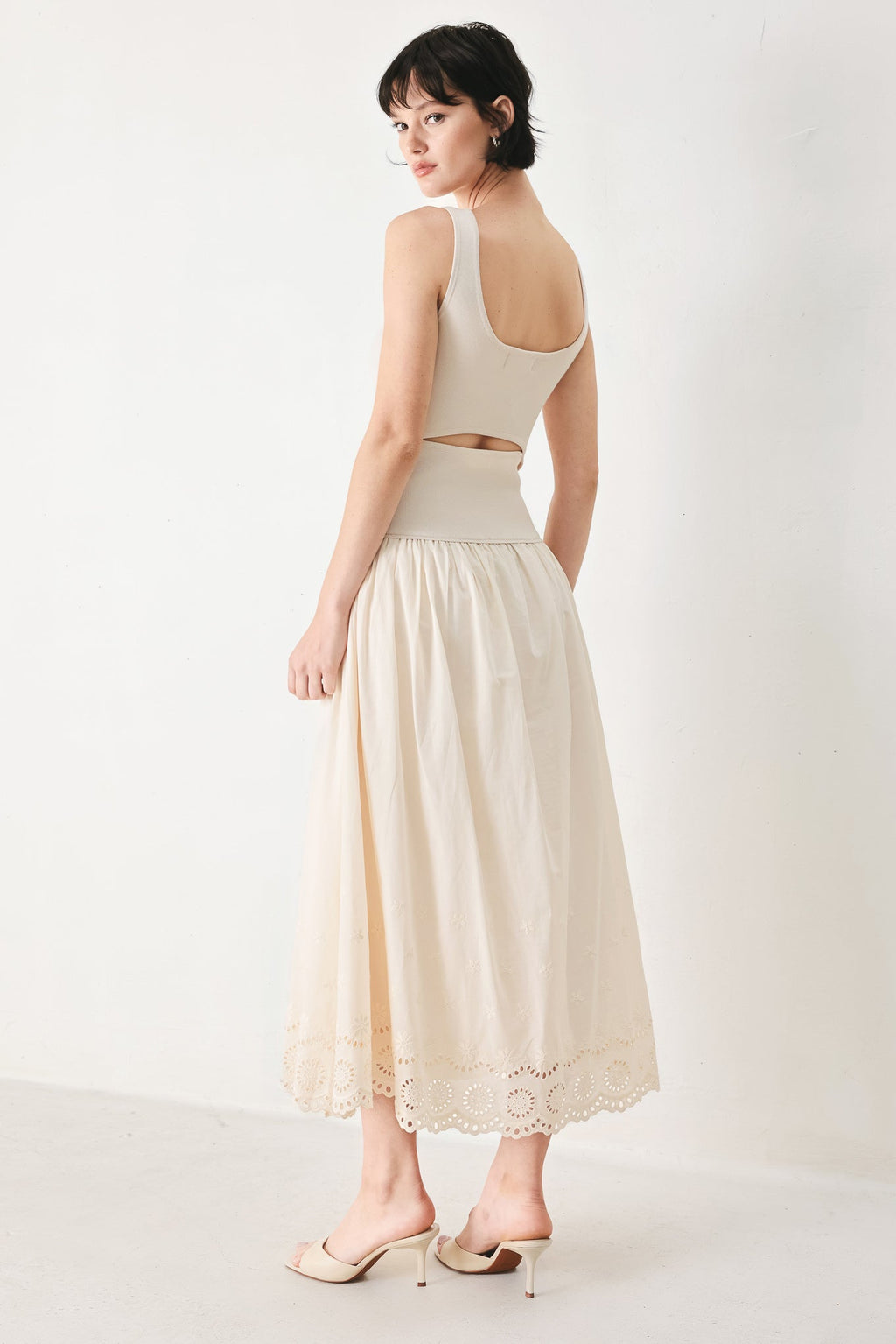 Daydream Thread Midi Dress in Light Taupe with sweater knit top, round neckline, sleeveless cut, drop waist, woven eyelet skirt, and cut out at waist shown on model