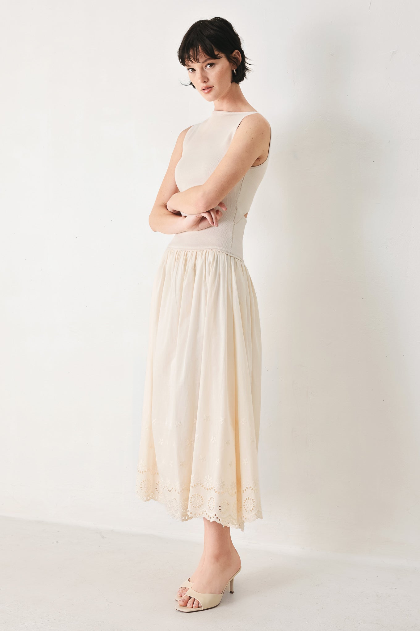 Daydream Thread Midi Dress in Light Taupe with sweater knit top, round neckline, sleeveless cut, drop waist, woven eyelet skirt, and cut out at waist shown on model