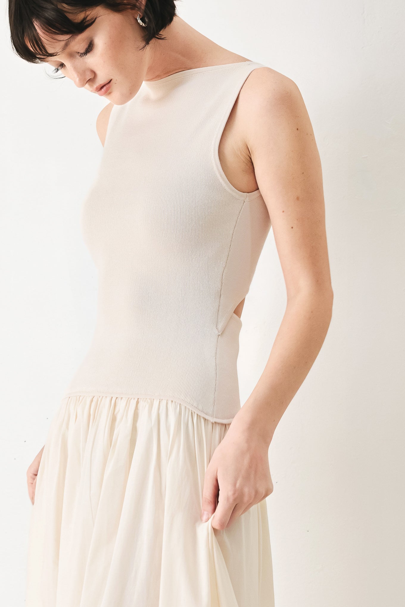 Daydream Thread Midi Dress in Light Taupe with sweater knit top, round neckline, sleeveless cut, drop waist, woven eyelet skirt, and cut out at waist shown on model