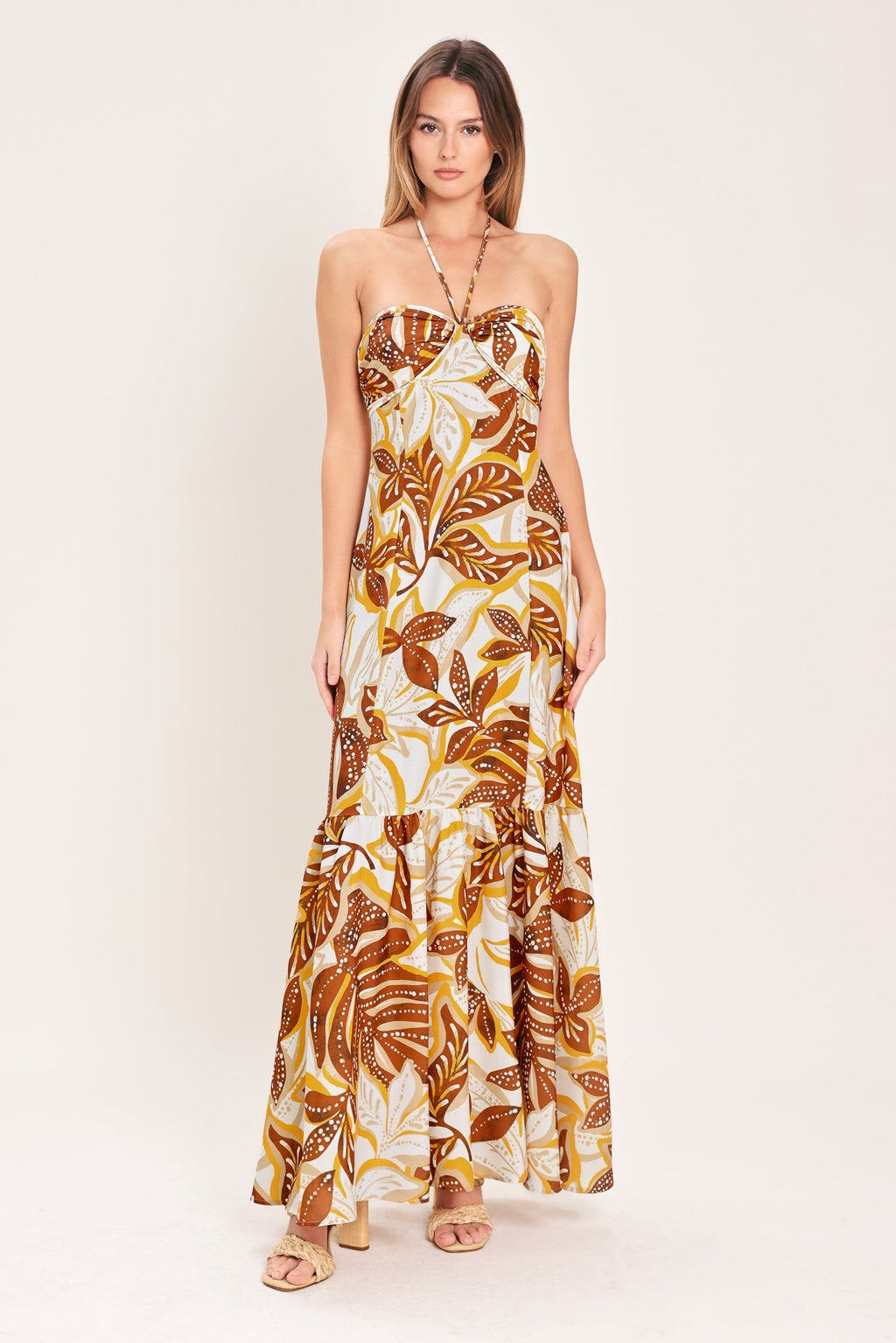 Amber Palm Paradise Woven Maxi Dress in Mustard Brown with palm print, halter tie neckline, ruffle hem, and back zipper closure shown on model