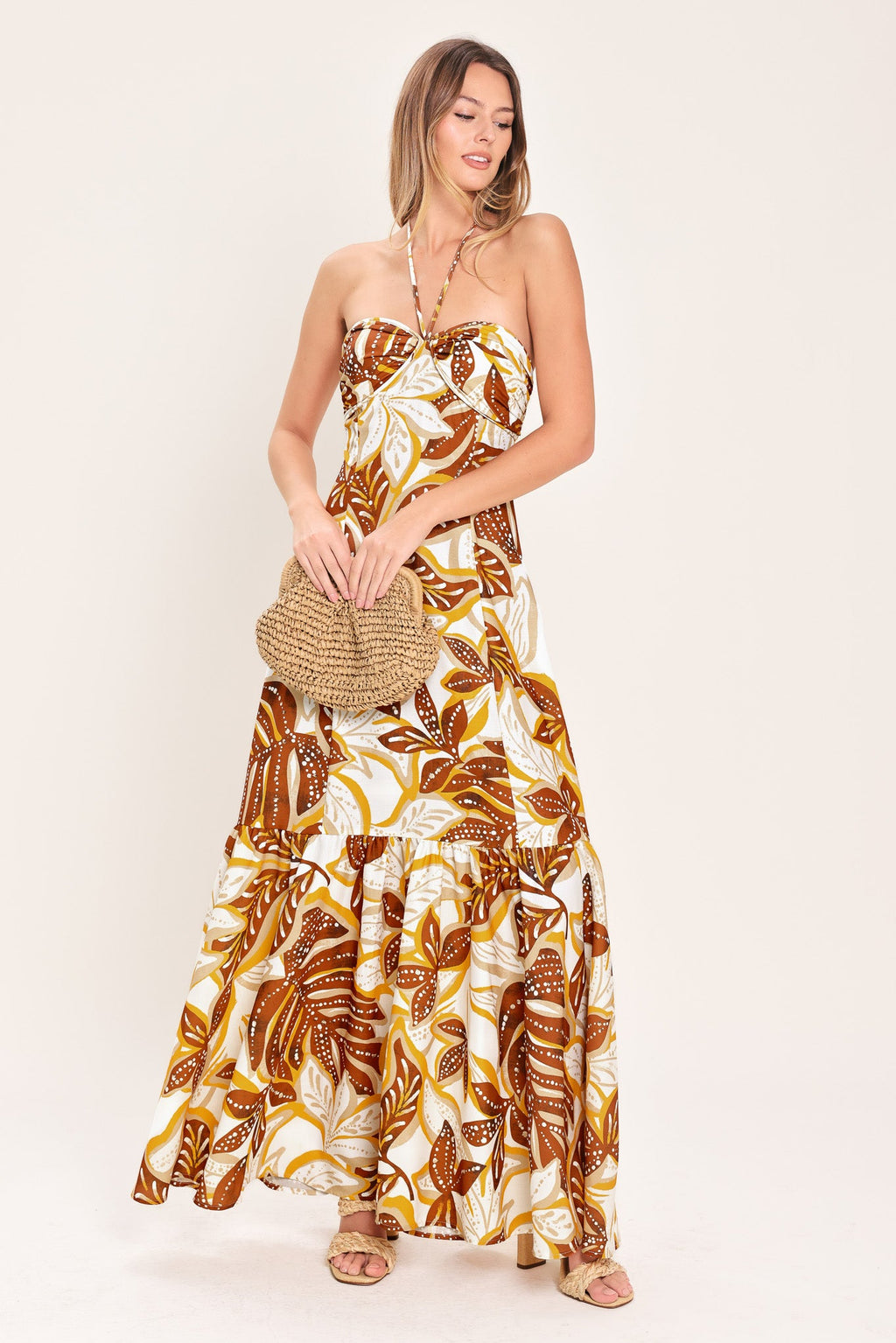 Amber Palm Paradise Woven Maxi Dress in Mustard Brown with palm print, halter tie neckline, ruffle hem, and back zipper closure shown on model