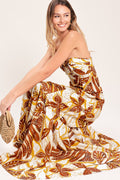 Amber Palm Paradise Woven Maxi Dress in Mustard Brown with palm print, halter tie neckline, ruffle hem, and back zipper closure shown on model