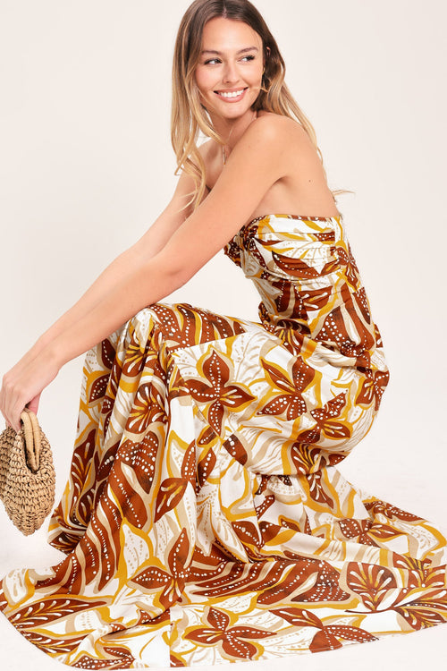 Amber Palm Paradise Woven Maxi Dress in Mustard Brown with palm print, halter tie neckline, ruffle hem, and back zipper closure shown on model
