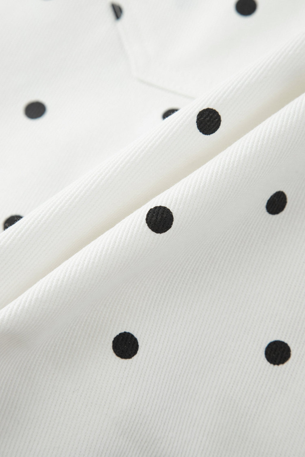 Close-up of polka dot embroidery on white denim shorts